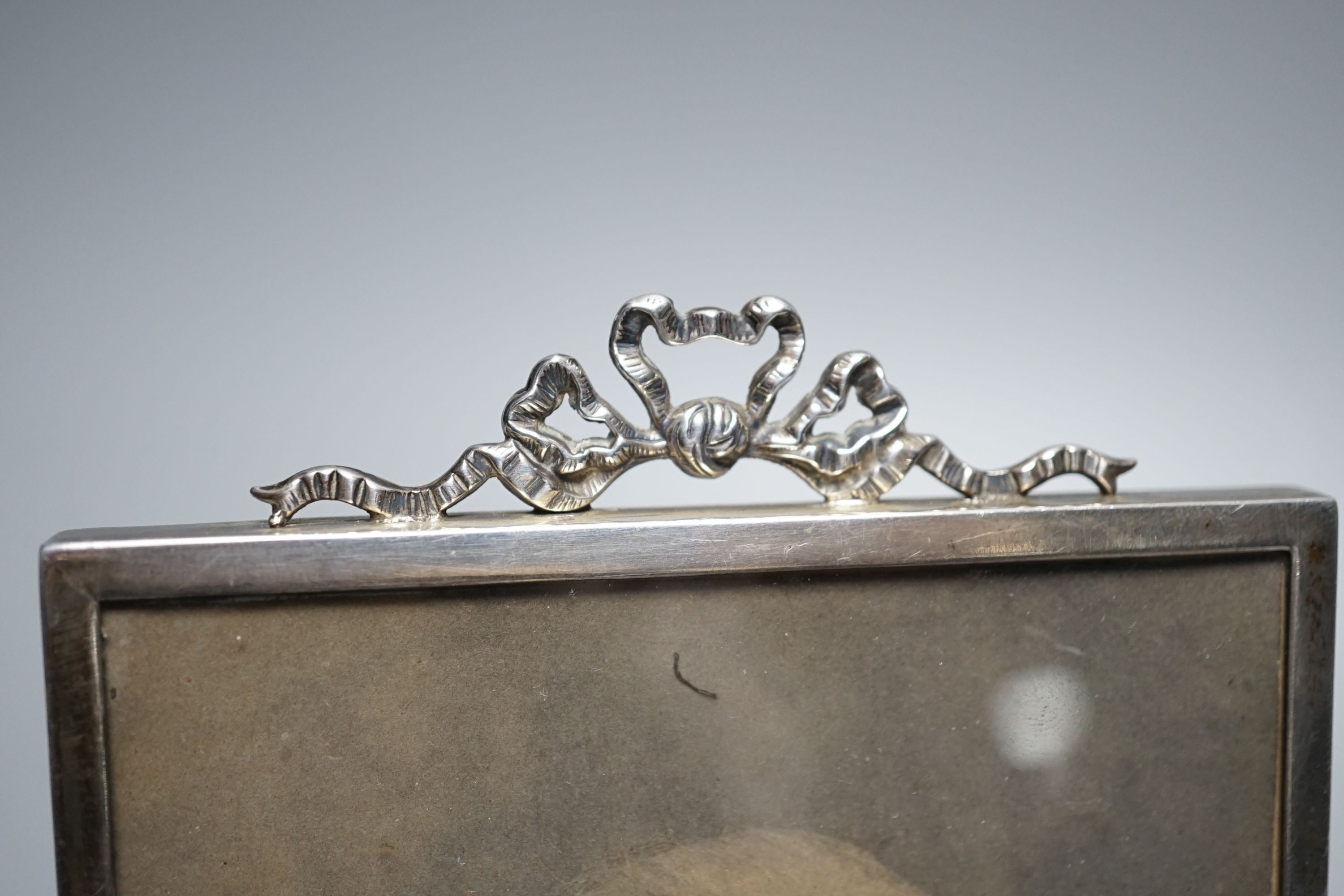 An Edwardian silver mounted photograph frame, with ribbon bow crest, Birmingham, 1902, overall 15.8cm.